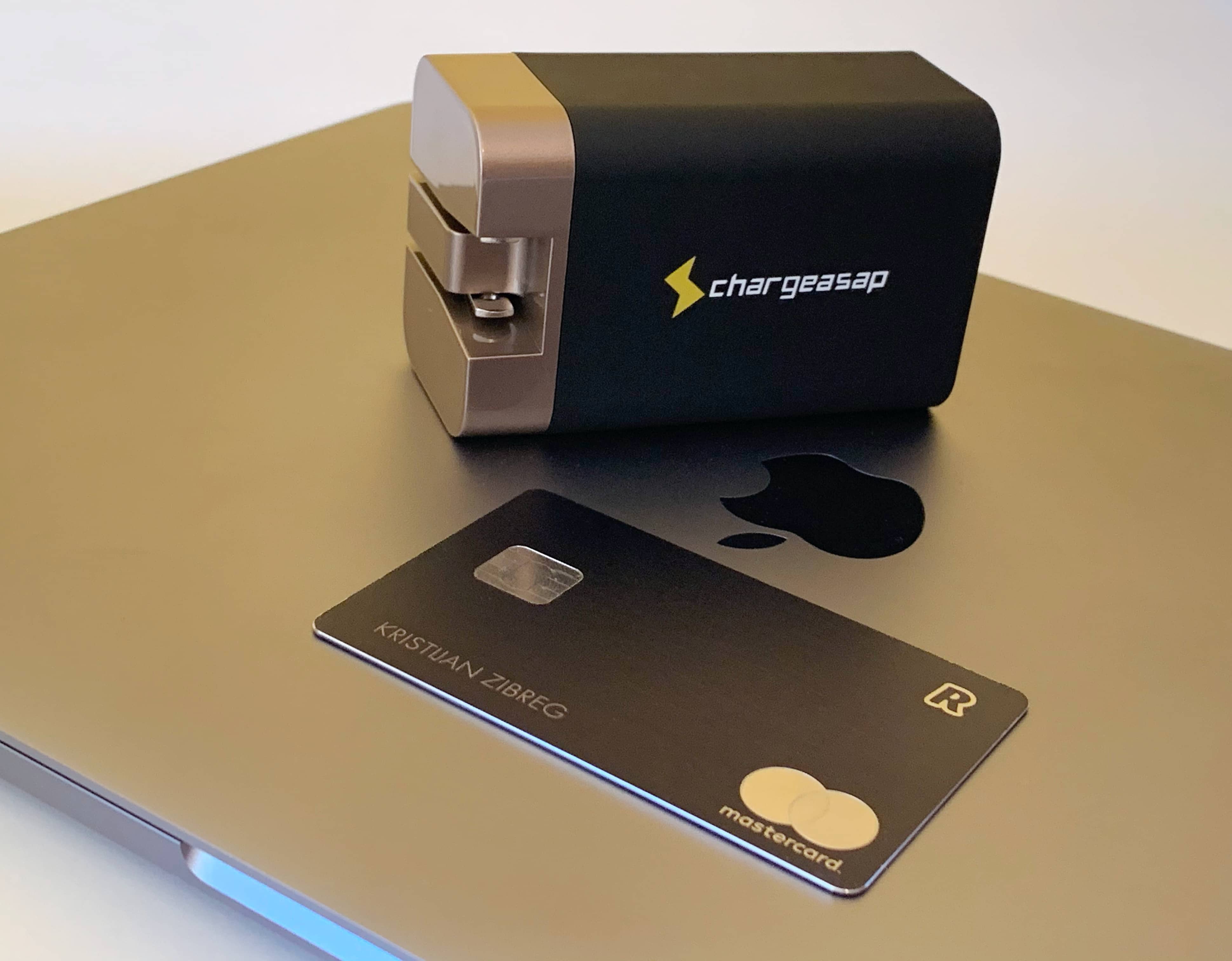 Caricabatterie Chargeasap Omega - Adattatore da 200 W seduto su un MacBook Pro con una carta di credito per il confronto delle dimensioni
