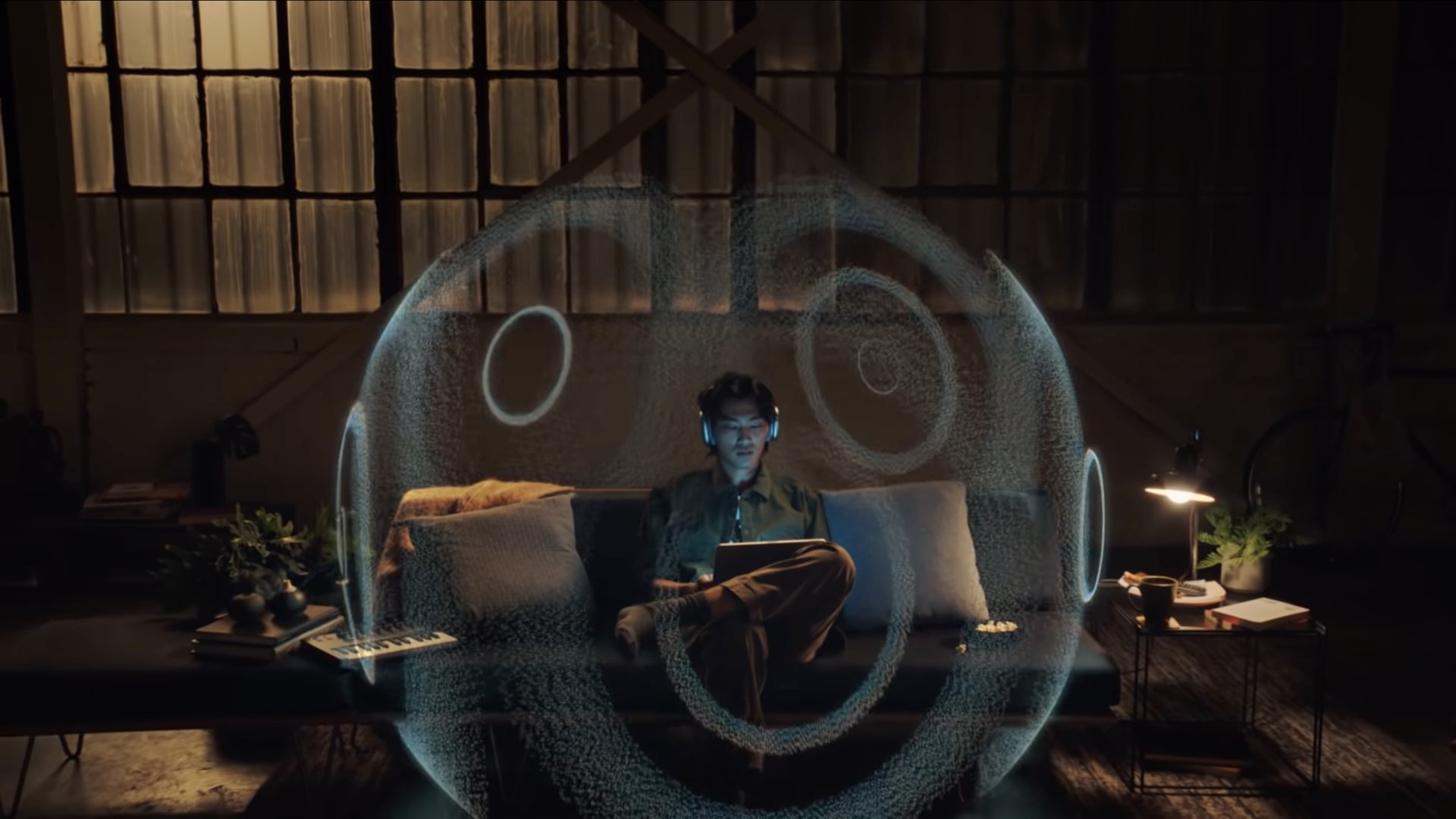 Un'illustrazione Apple che mostra una persona seduta sul divano, che indossa AirPods Max e si gode l'audio spaziale
