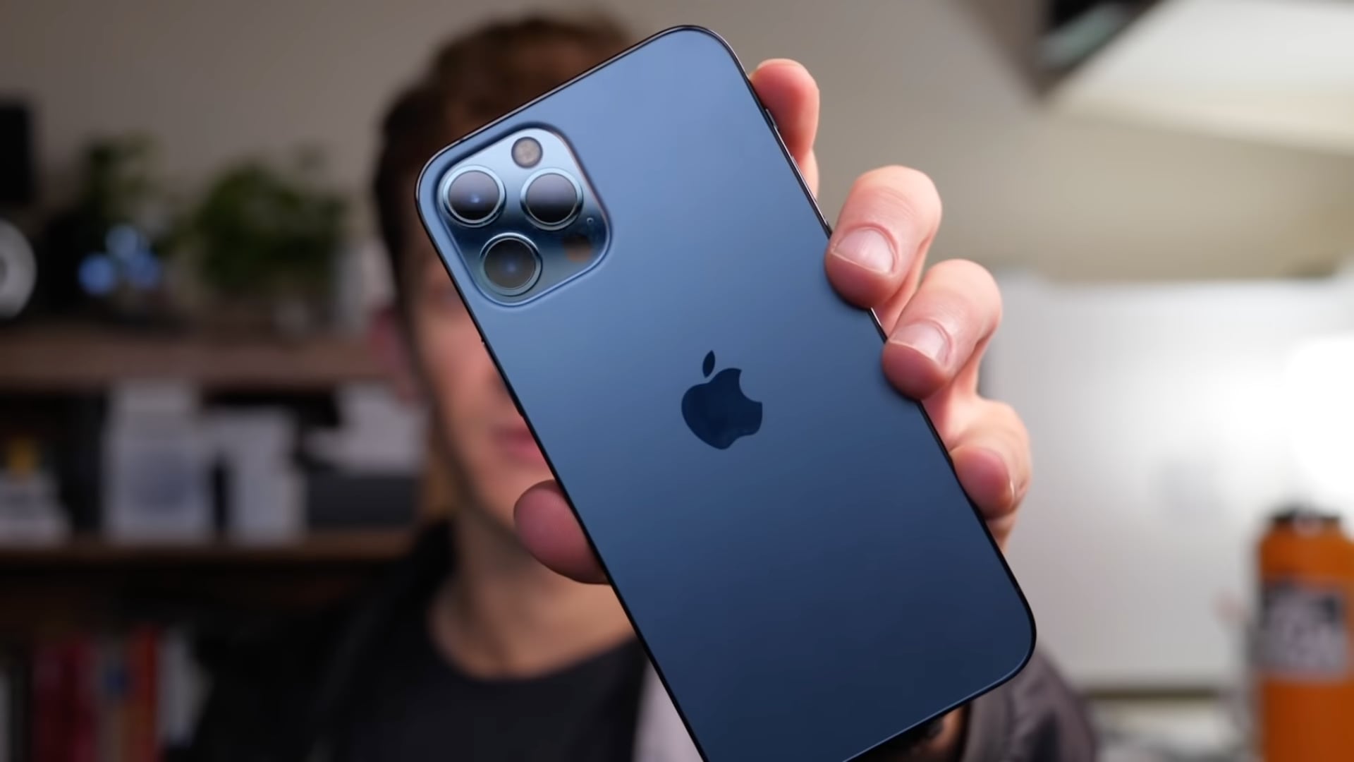 Un fermo immagine tratto dal video di tuttotutorial su 10 funzioni nascoste di iPhone 13, con l'host Harris Craycraft che mostra un iPhone 13 Pro Max blu in mano alla fotocamera